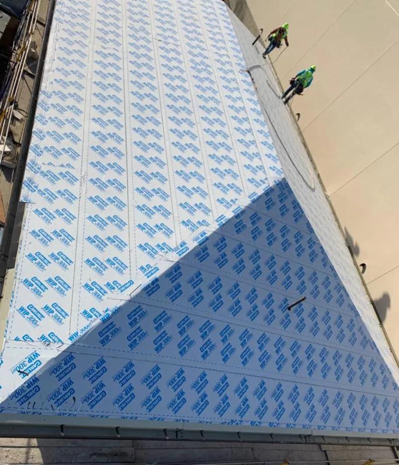 Professional roofers installing underlayment on a metal roof in Narragansett